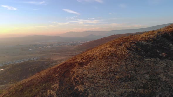 Aerial rotating shot of a large mountain near Colima in Mexico at sunset. alt