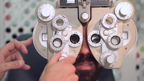 Close Up Shot of Optometrist in White Coat Changing Lenses on Phoropter Instrument and Talking alt