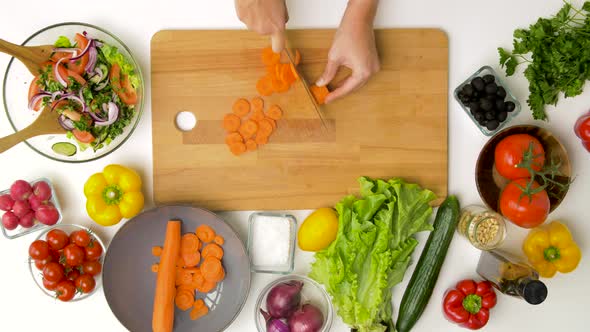 Woman Chopping Carrot with Kitchen Knife at Home alt