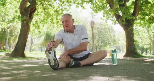 Senior man stretching his legs in the park alt