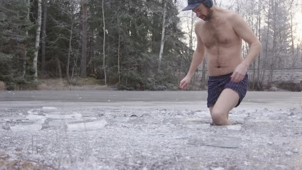 A trendy ice bather steps into the ice hole and begins his cold water exposure alt