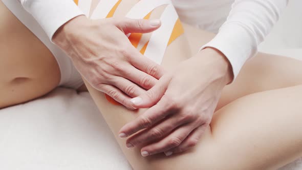 Therapist is applying kinesio tape to female body. Physiotherapy, kinesiology and recovery. alt