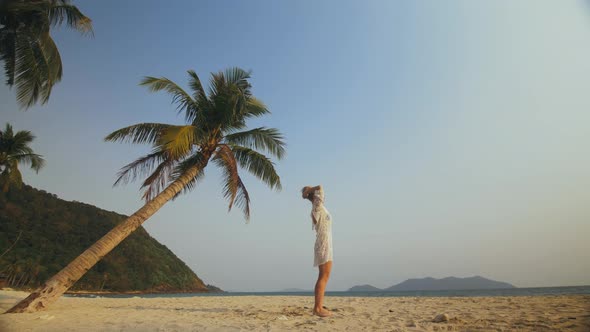 Woman in a White Tunic on Beach Near the Sea Palm Tree
