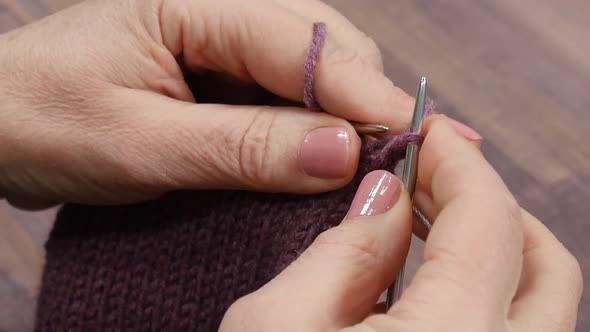 Woman Knits Mittens From Purple Yarn