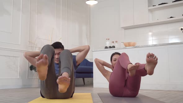 Asian couple pumping the abdominal exercise on yoga mat