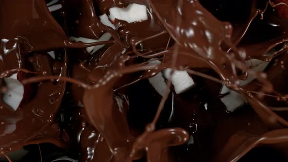 Super Slow Motion Shot of Coconut Pieces Falling Into Melted Chocolate at 1000 Fps alt