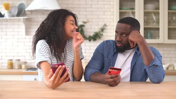 The Multiracial Couple Using a Smartphone for Shopping Online at Home alt