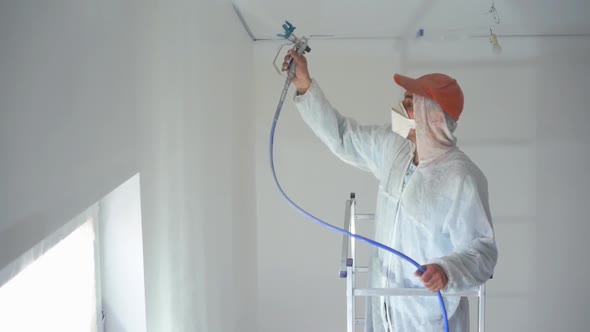 Professional Painter Paints the Walls with White Paint