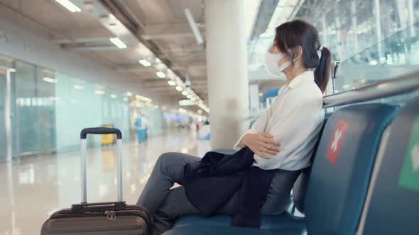 Asian business girl walk with luggage sitting in bench wait and look partner for flight at airport.