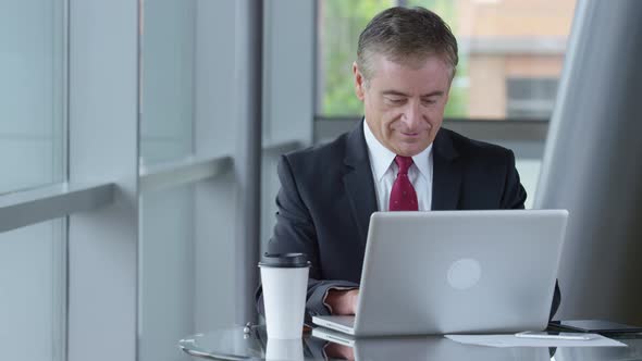 Mature businessman using laptop computer in office lobby