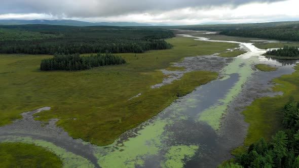 Aerial shot dropping down above the still waters of Shirley Bog winding through the Maine countrysid alt