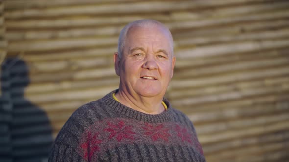 Portrait of an Elderly Man Dressed in Ordinary Clothes Standing Near an Old Wooden Barn