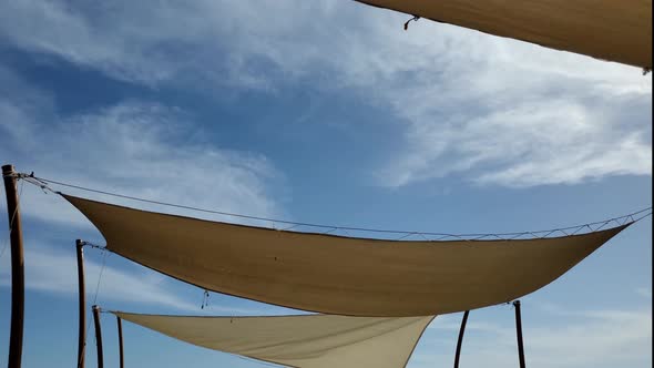Fabric Sunshades Sway in Wind with Blue Sky and Floating White Clouds Time Lapse