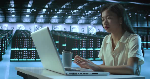 Asian Female IT Technician Using Laptop Doing Maintenance and Diagnostics in the Server Room