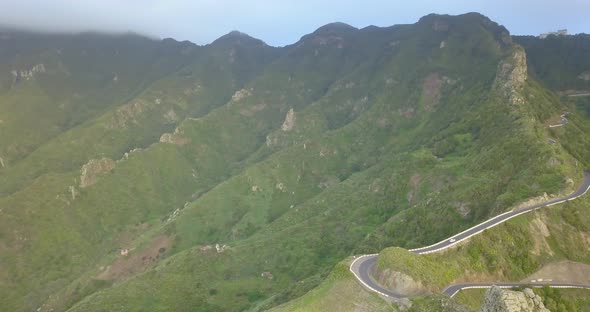 Aerial drone view of green mountains and road in Tenerife, Spain. alt