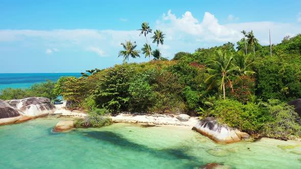 Rocky tropical shore with tall palms and exotic lush. white sandy beach and turquoise sea water alt