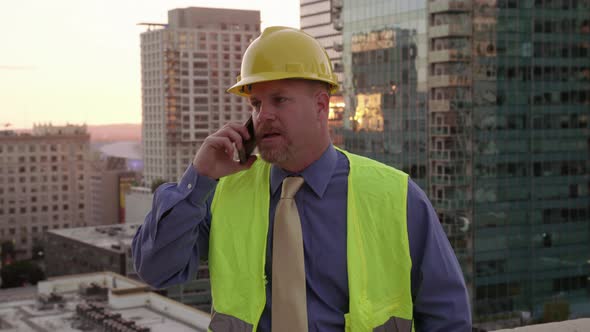 Construction manager on rooftop using cell phone