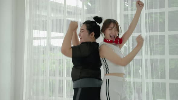 beautiful Asian woman and fat woman practicing dancing in the room cheerful and happy.