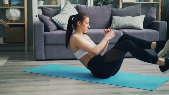 Sporty Young Woman Doing Abs Exercises Moving Body on Yoga Mat in Apartment alt