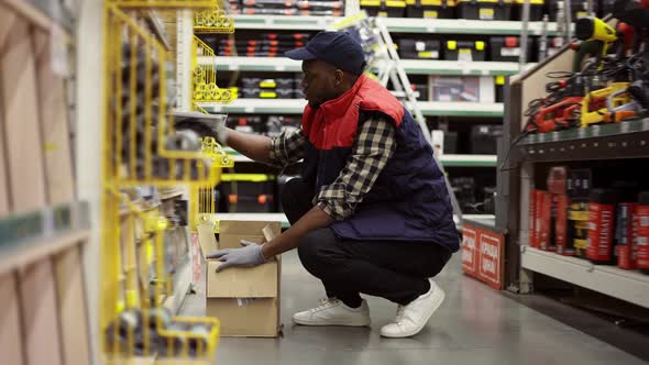 Male Worker Refill Goods on Lower Shelves of Hardware Store alt