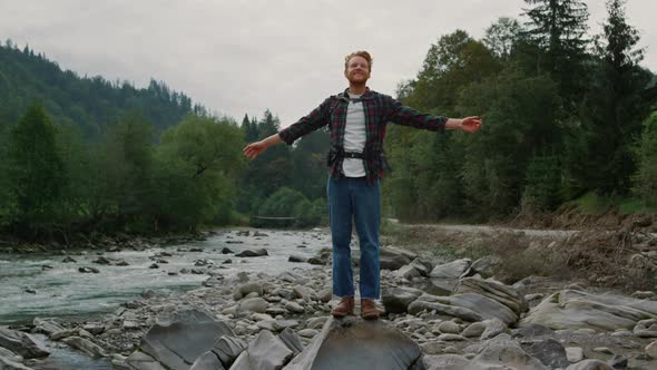 Guy Standing on Rock at River Shore alt