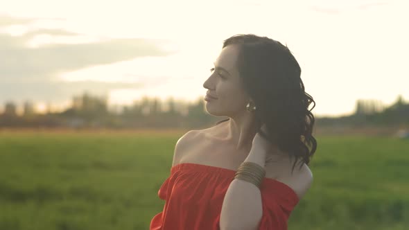 Portrait of a Beautiful Spanish Brunette Woman in a Red Dress at Sunset in a Wheat Field alt