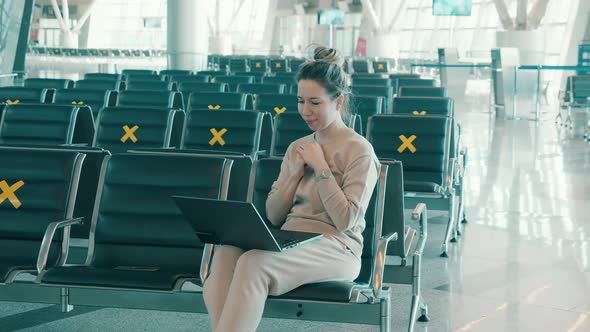 A Woman with a Laptop in the Empty Departure Lounge alt