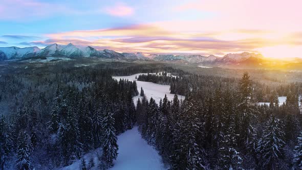 Snow capped mountains in the winter, at colorful sunset, aerial view.