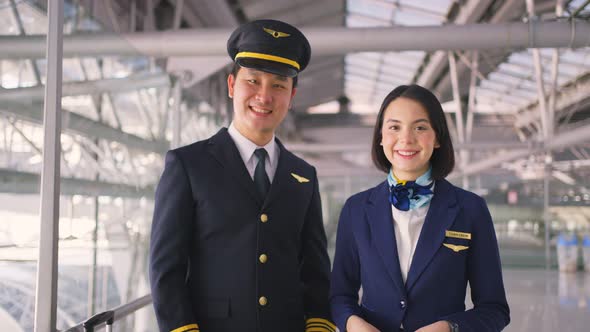 Airliner pilot and air hostess removing face mask in airport terminal after the COVID pandemic. alt