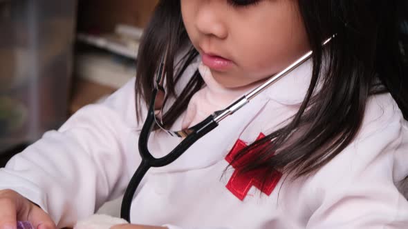 Cute young girl playing doctor with stethoscope and stuffed toys at home. alt