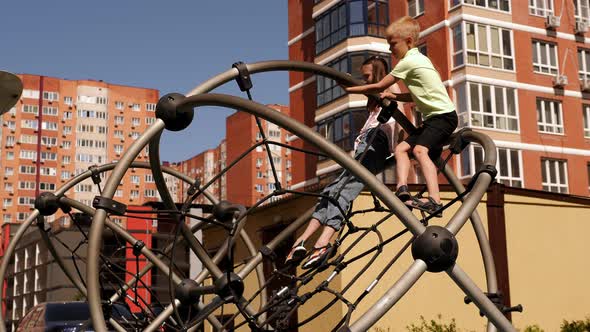 Children Climb Ropes and Pipes on a Modern Playground in the Courtyard alt
