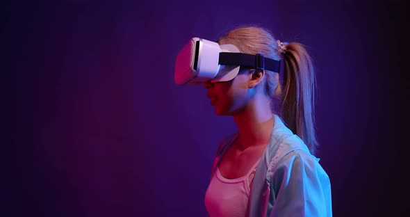 Young Asian woman playing metaverse virtual reality digital technology game with VR goggle. alt