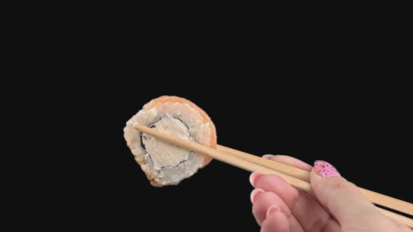 Female Hands Hold Japanese Chopsticks with Sushi Rolls on Transparent Background alt