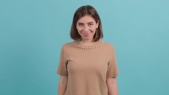 Happy Woman Showing Thumbs Up Gesture Isolated Over a Turquoise Background alt