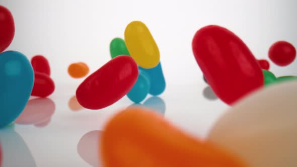 Camera follows jelly beans falling on surface. Slow Motion. alt