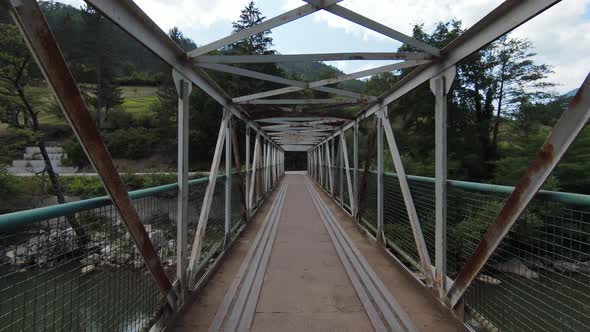 Skilled Flying of FPV Drone Inside Iron Bridge Over the River on Sunny Summer Day alt