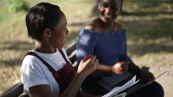 Smiling Happy African American Female Student Gesturing Victory Highfive with Friend Sitting in alt