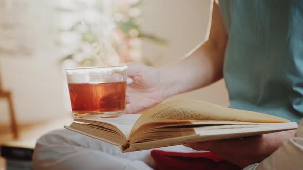 Sunset Book (21)Woman Holding Steaming Cup of Tea or Coffee and Reading a Book.