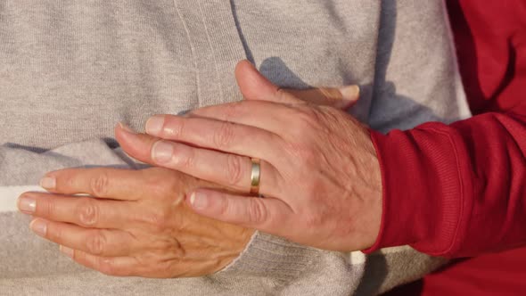 Senior Caucasian Married Couple Hugging Covering Their Hands Closeup alt