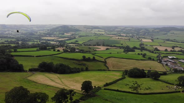 Aerial shot of a Paraglider flying over the Devon Countryside in England alt