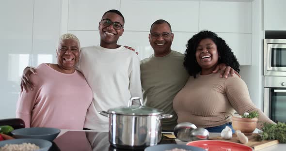 Happy latin family looking in camera and smiling - Parents and adult children having fun cooking alt