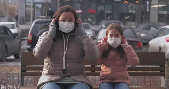 A Mother and Her Daughter Put Protective Masks on