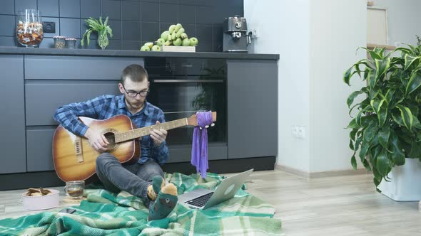 Man playing guitar in kitchen in self isolation. Musician playing acoustic guitar at home alt