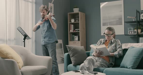 Woman annoyed by her husband playing violin at home