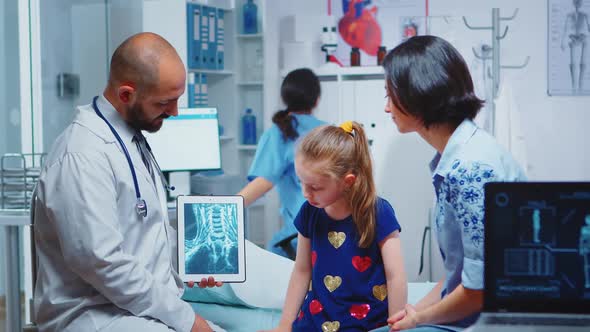 Male Pediatrician Checking Bone Xray on Tablet alt