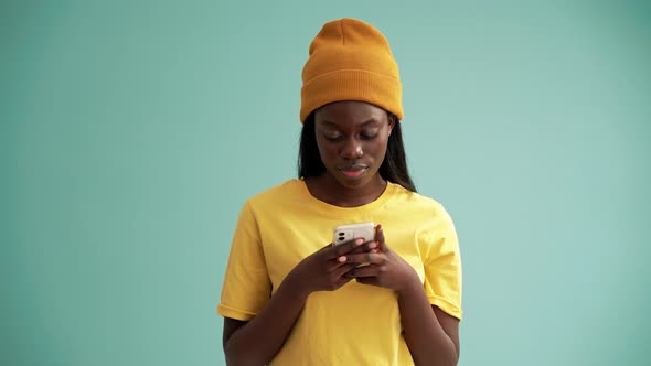 Positive African woman texting by phone alt