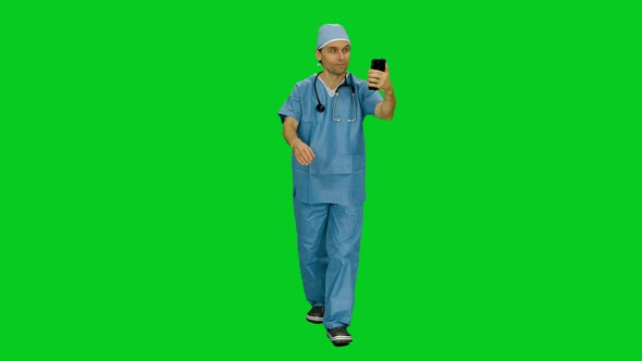 Male Surgeon In Uniform Talking Via Smartphone While Walking on Green Screen