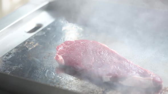 Cooking raw beef steaks on the stove with tongs