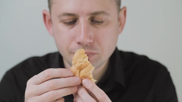 Man Eating Croissant with Egg and Sausage. Emotionally Chewing on the Bloodsucker. A Hungry Man alt