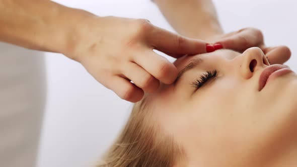 Beautician cosmetologist makes face sculpt kobido massage areas forehead alt
